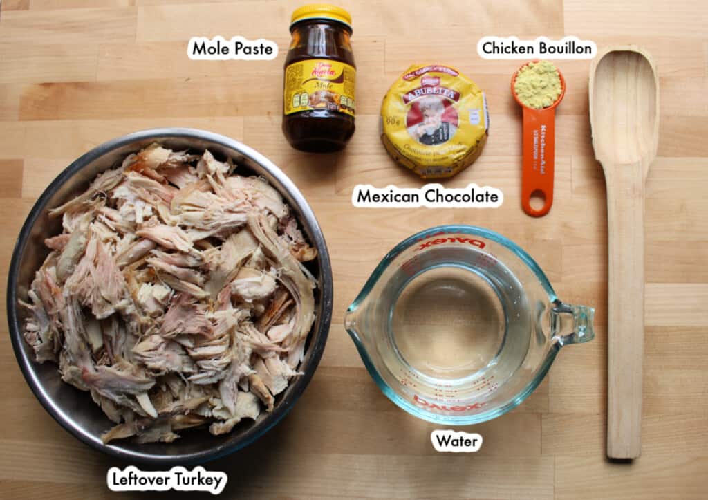Los ingredientes necesarios para hacer un mole de pavo rotulados y sobre una superficie de madera.