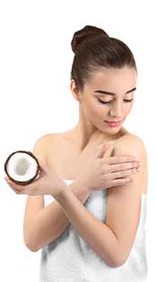 Chica usando aceite de coco fraccionado en la cara como humectante.