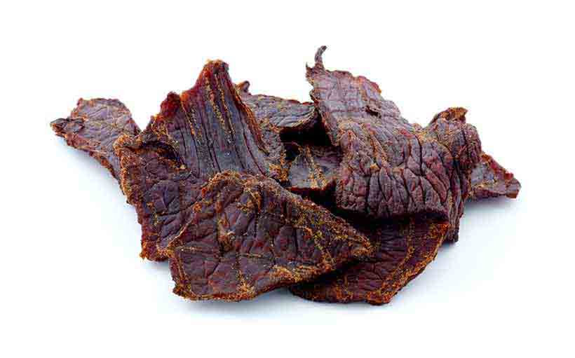 Beef Jerky: el popular bocadillo de carne seca. Trozos De Carne Seca Sobre Un Fondo Blanco.