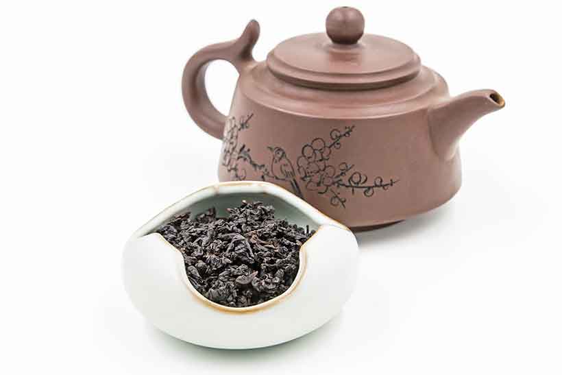 Hojas de té chino tradicional Oolong cerca de la tetera. Hojas de té oolong y tetera china.