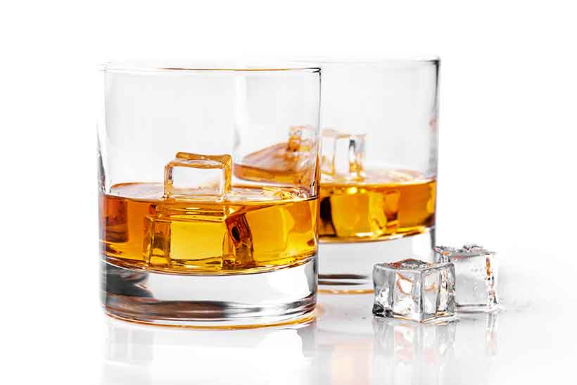 Dos vasos de whisky con cubitos de hielo. Dos vasos de whisky uno al lado del otro, llenos de cubitos de hielo.