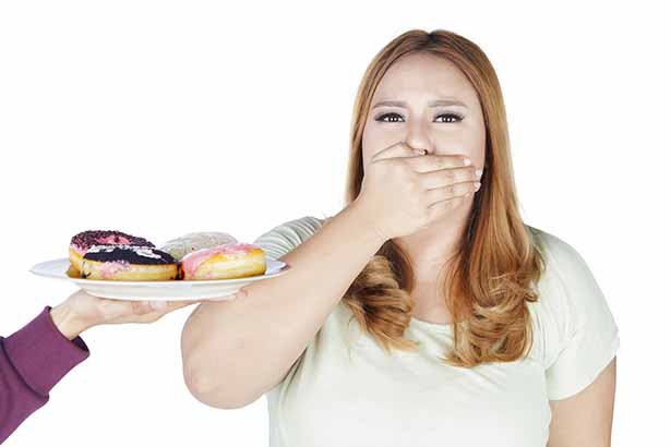 Mujer tapándose la boca con la mano cuando le ofrecen un plato de carbohidratos filtrados.