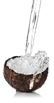 Imagen de coco fresco cortado por la mitad con agua salpicada.