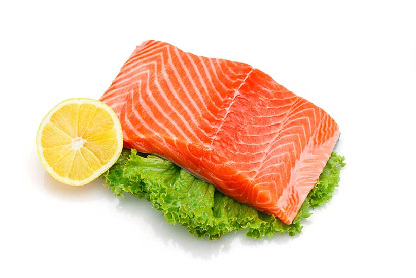 Filete de salmón grande servido con lechuga y medio limón.