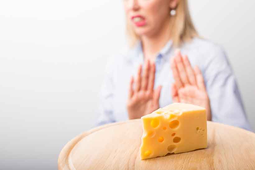 Mujer haciendo gestos diciendo que no quiere queso cheddar.