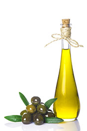 Botella de aceite de oliva virgen extra junto a unas aceitunas.