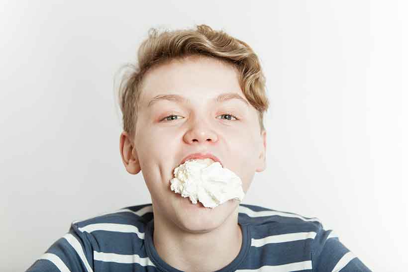 Un niño con la boca llena de crema espesa.