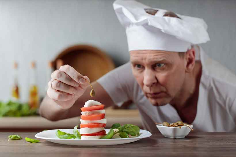 Las alcaparras funcionan bien como decoración de ensaladas. Chef Decorando Ensalada Con Alcaparras Y Mozzarella.