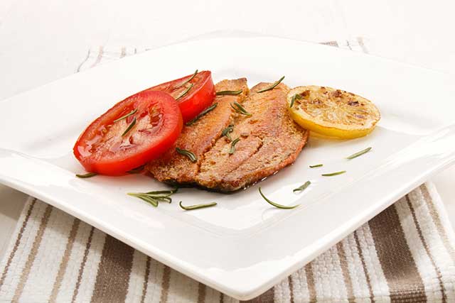 Arenque Asado A La Parrilla En Un Plato Con Limón Y Tomate.