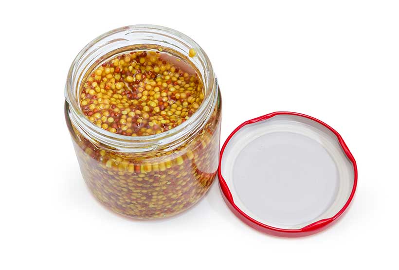 Tarro de cristal de mostaza en grano y sin tapa.