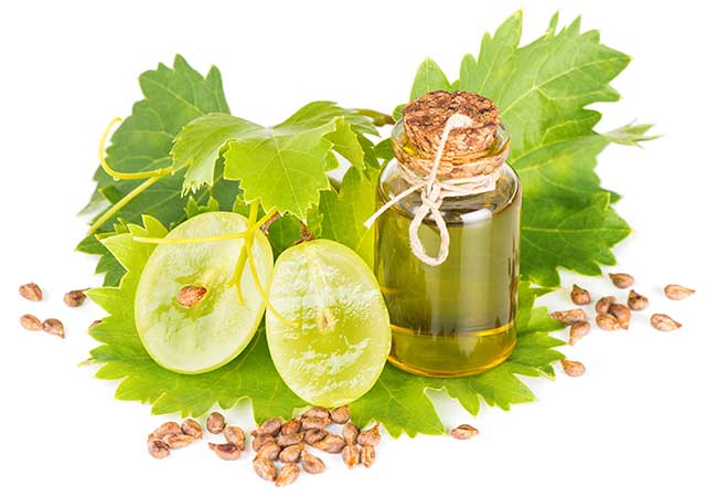 Botella de aceite de semilla de uva cerca del racimo de uvas verdes.