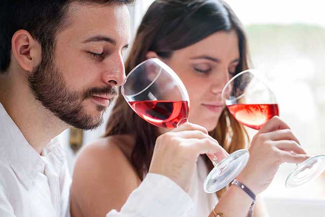 Hombre y mujer bebiendo vino rosado.
