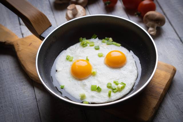 Dos huevos fritos en una sartén negra.