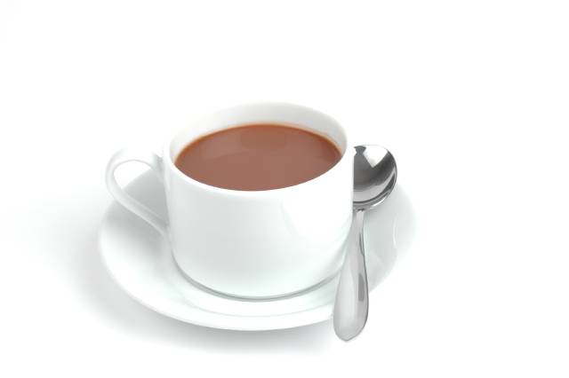 Chocolate caliente en una taza blanca sobre un platillo con una cucharadita.