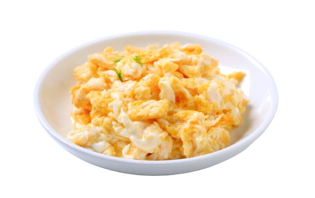 Huevos revueltos en un tazón blanco pequeño.
