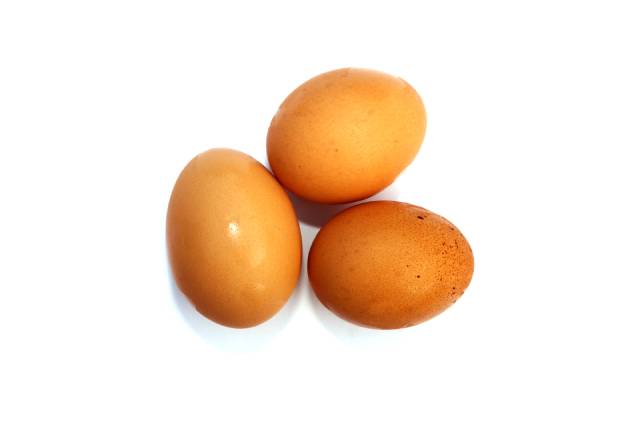 Tres huevos de gallina enteros uno al lado del otro.