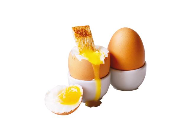 Dos huevos pasados por agua en hueveras: uno entero, uno abierto con yema de naranja líquida.
