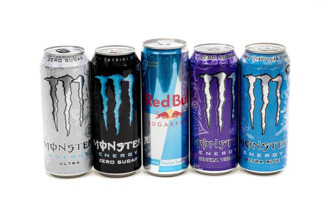 Varias latas de bebidas energéticas en línea (Red Bull, Monster).