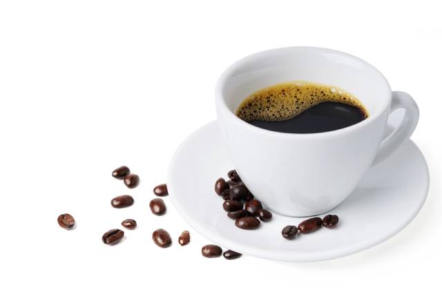 Una taza blanca llena de café negro sobre un blanco puro.